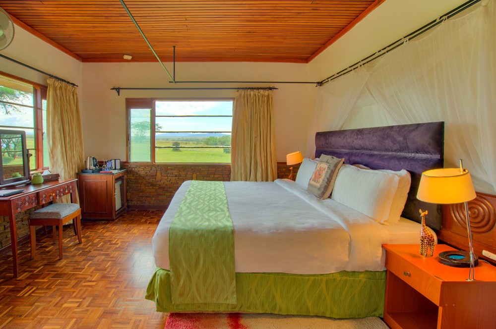Lodge bedroom at Muthu Keekorok Lodge with a king bed, mosquito net, wooden ceiling, and savannah views